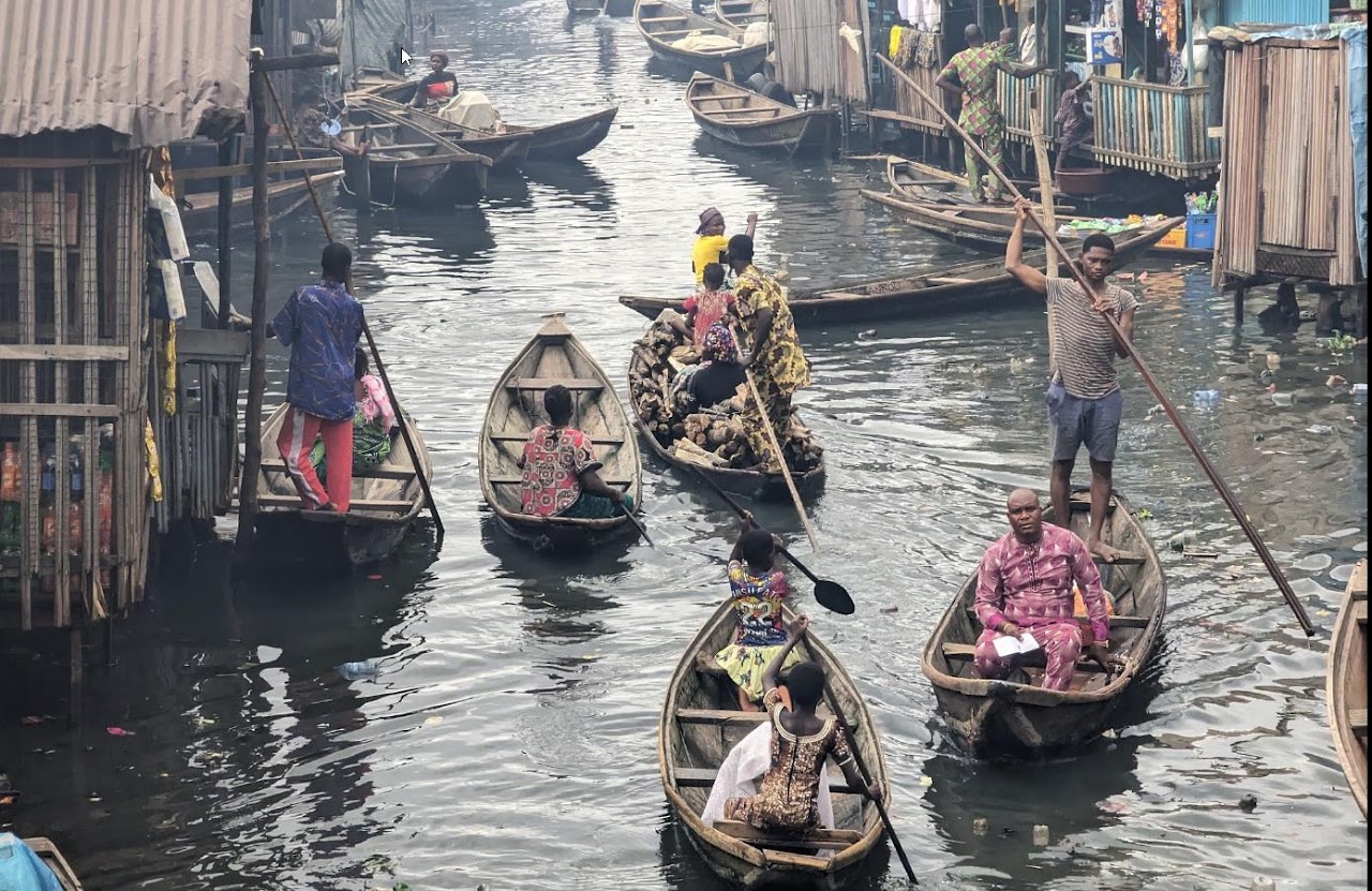 Aerial view of Makoko floating village — traditional wooden boats on the Lagos lagoon