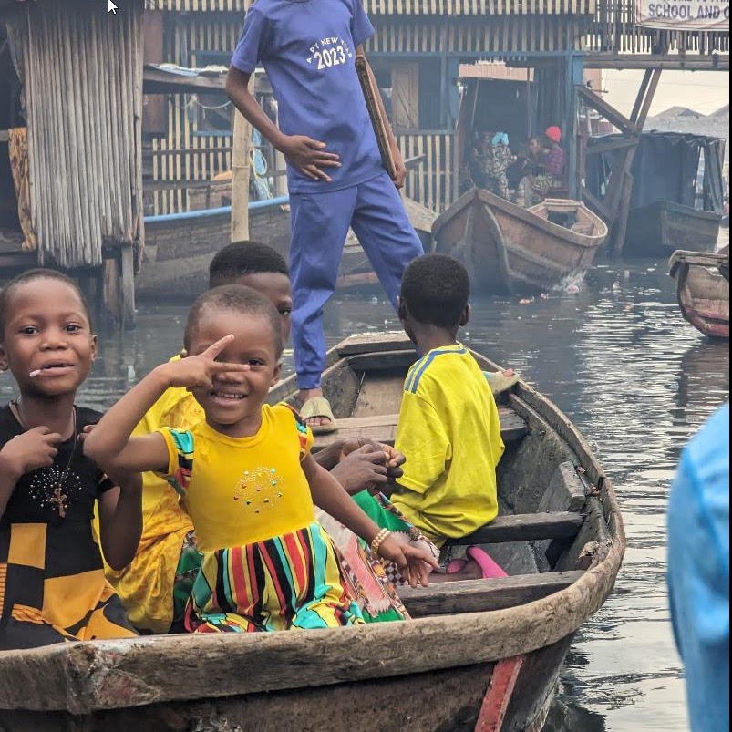 Children smiling in colourful traditional boats in the Makoko waterways of Lagos