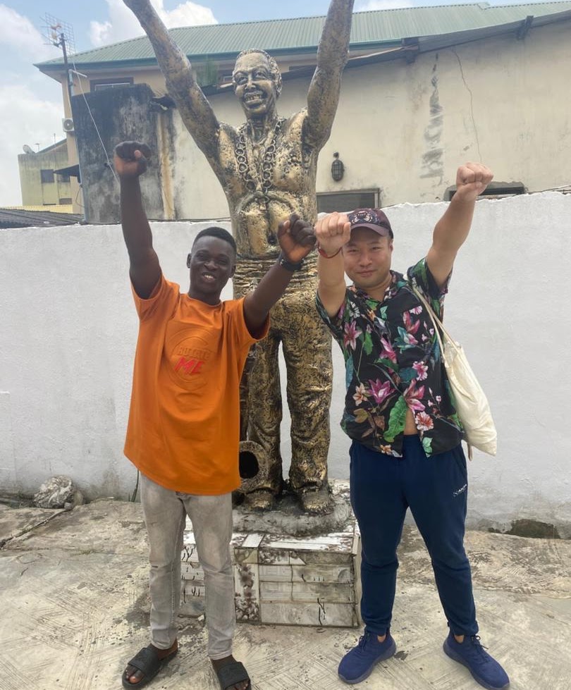 Benjamin and a traveller posing at a cultural statue in Lagos